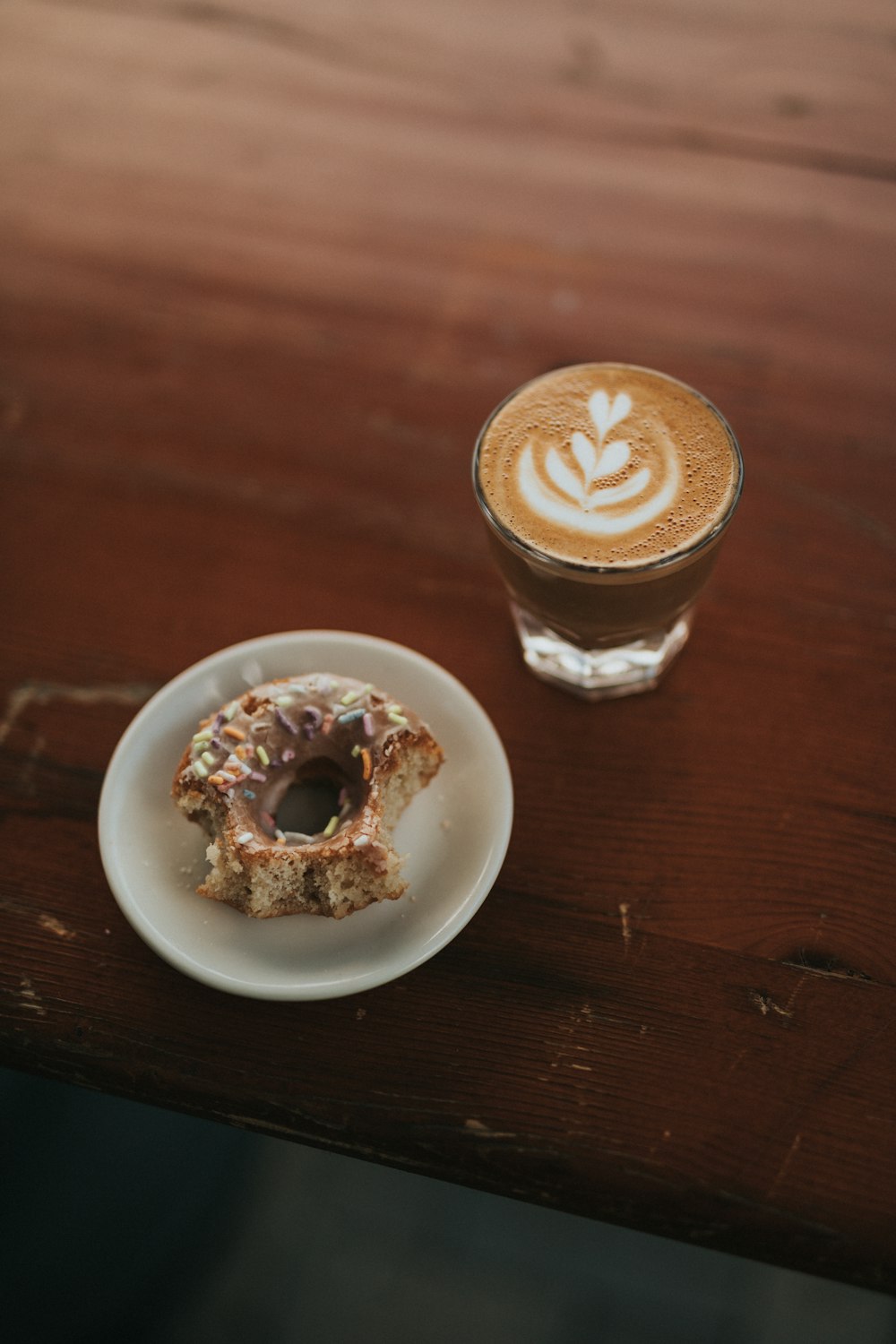 bitten donut beside coffee cup on table