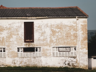 Exterior façade being coated with cement plaster under bright daylight.