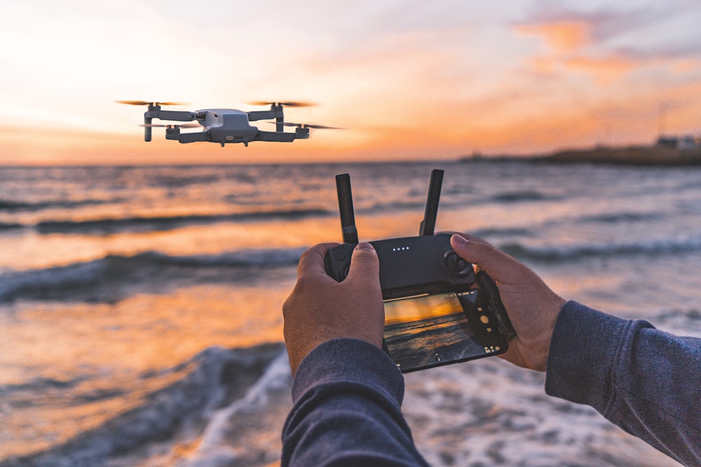 Persona que opera un dron que vuela sobre la orilla del mar