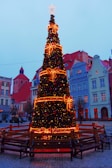 Children decorating a large Christmas tree in the town square.