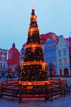 Children decorating a large Christmas tree in the town square.