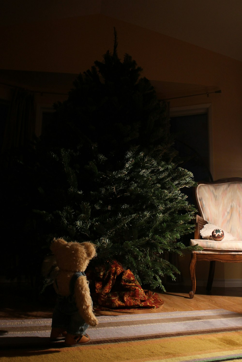 brown bear plush toy in front of green holiday tree