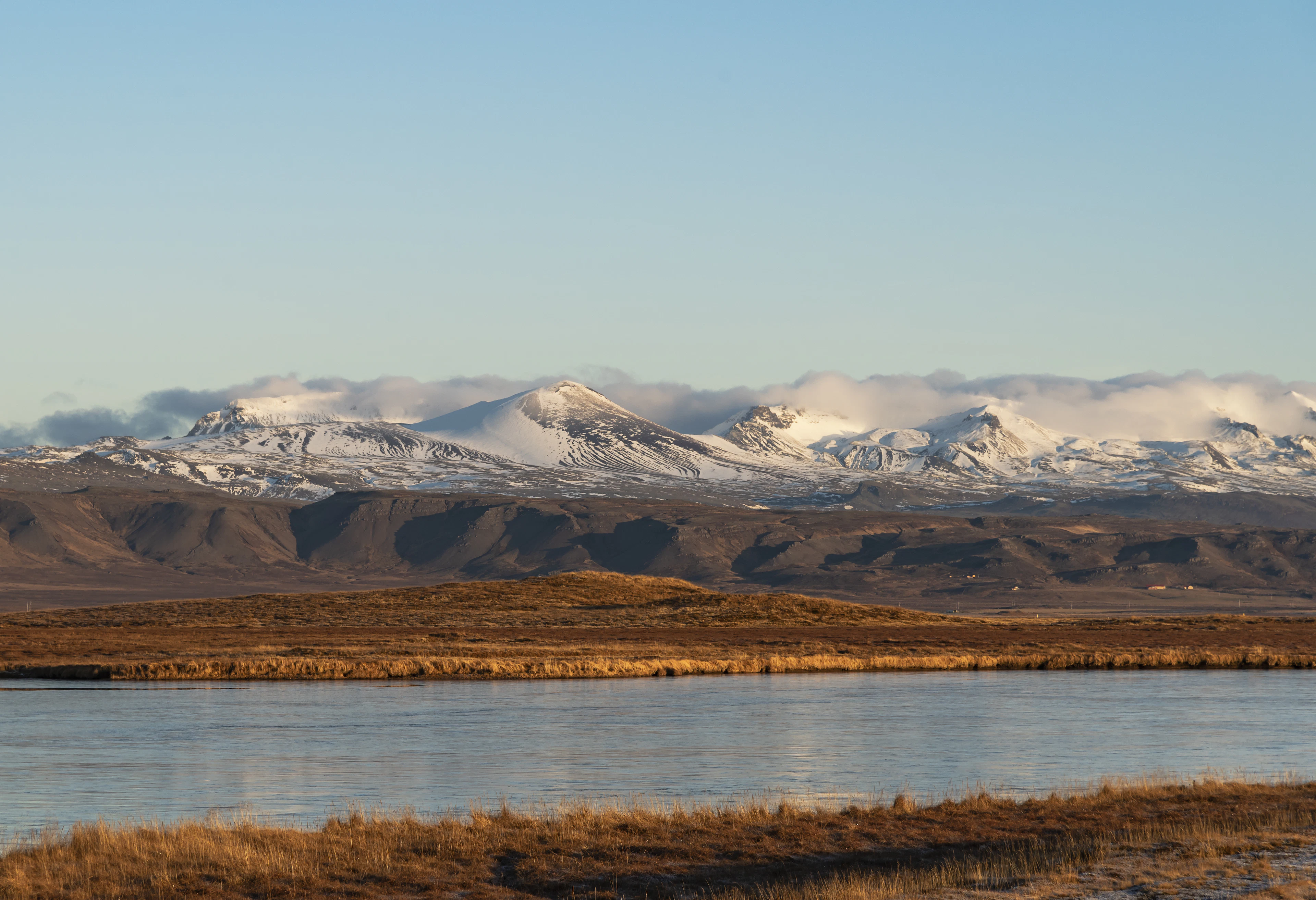 Snow-covered peaks around Snæfellsjökull above calm water and golden grassland on the Snæfellsnes peninsula