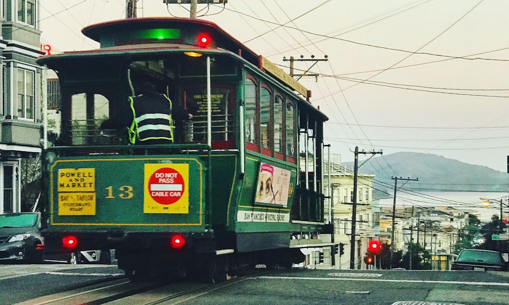 green tram passing by the street