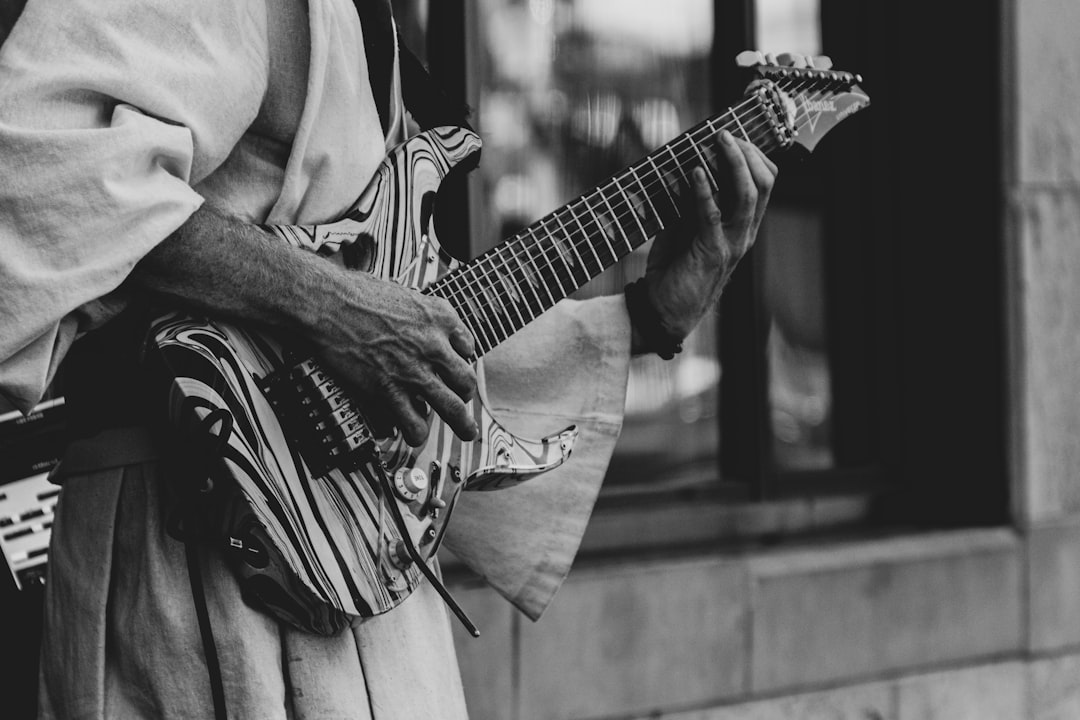 grayscale photography of man playing electric guitar
