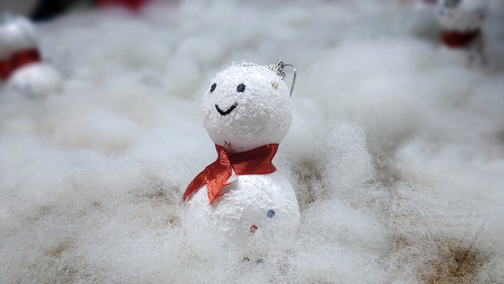 a snowman with a red bow tie sitting in a pile of snow