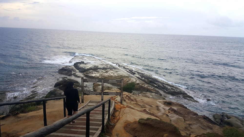 person walking down a stairs leading to the beach