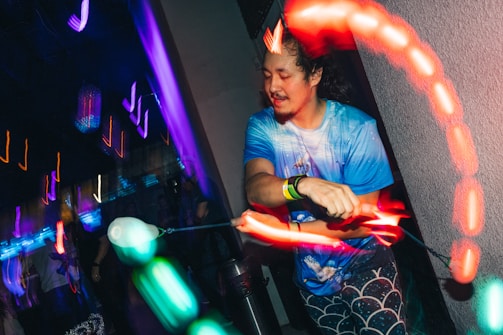 Artist holding a glowing hoop mid-spin with a joyful expression.