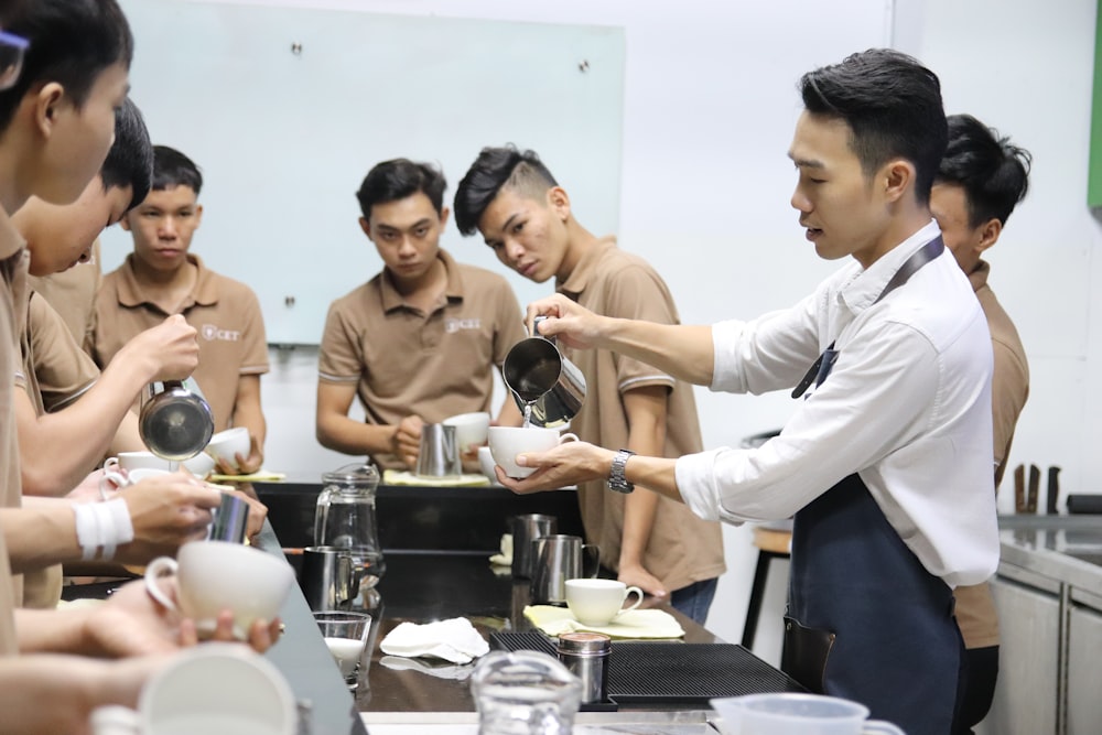 man pouring beverage on white cup