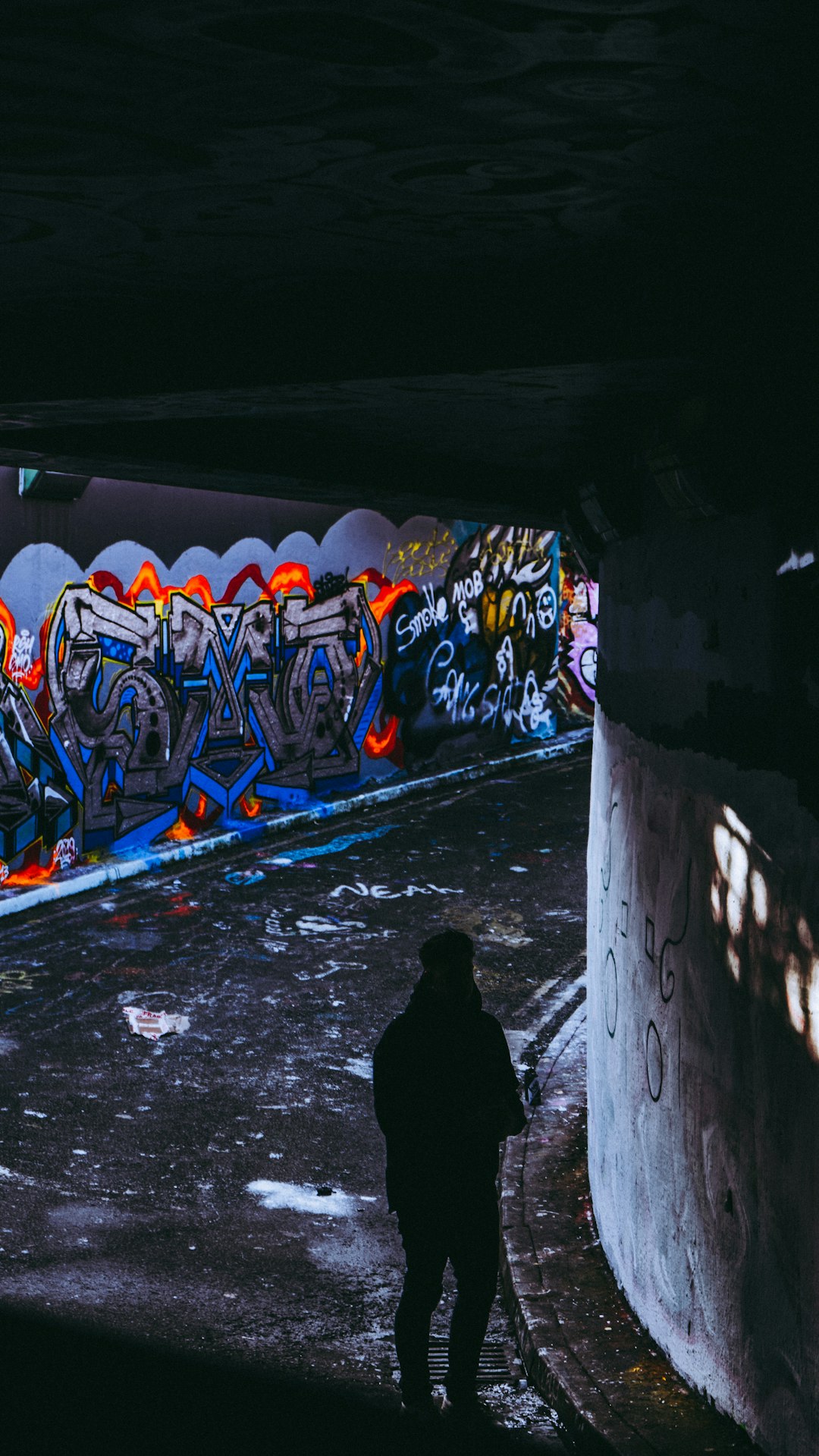 man in tunnel near graffiti