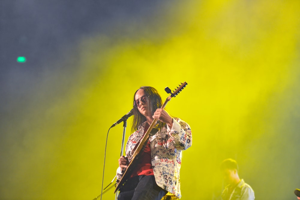 um homem segurando uma guitarra enquanto está em pé em um palco