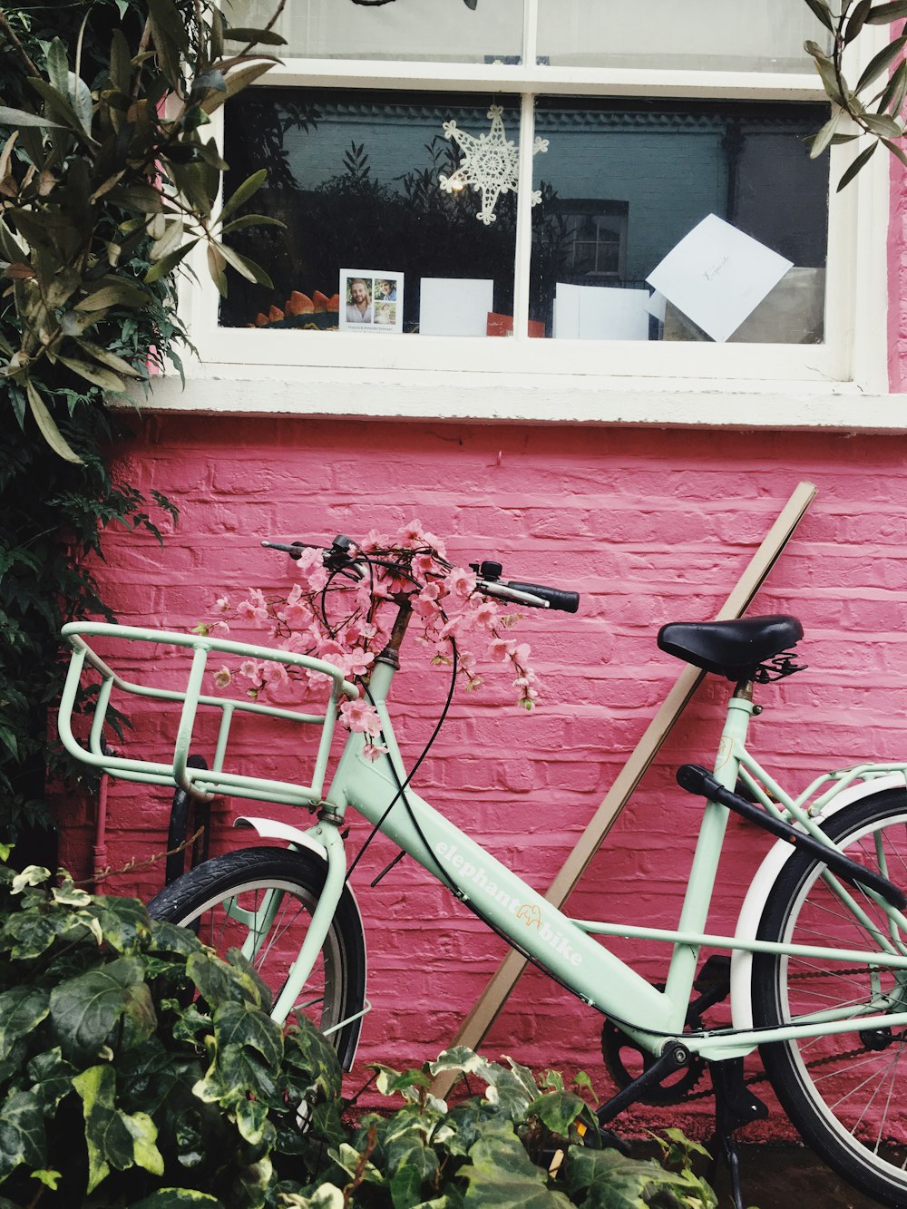 white commuter bike leaning on house