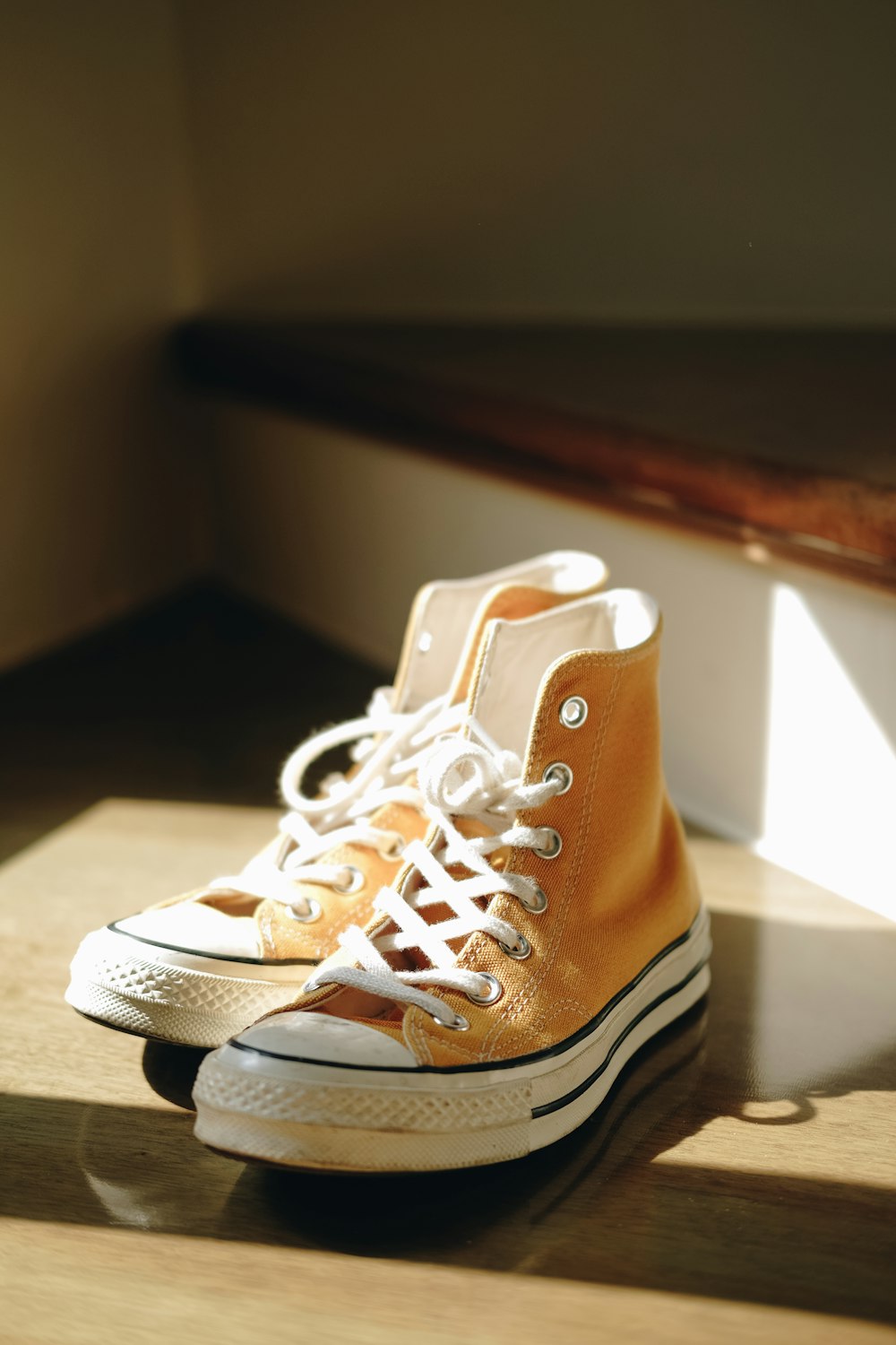 sneakers alte Converse All-Star gialle e bianche su scala in legno marrone