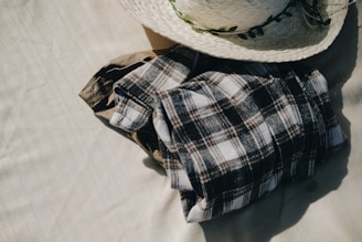 A flat lay of folded linen shirts and straw hats on a rustic table, evoking relaxed island vibes.