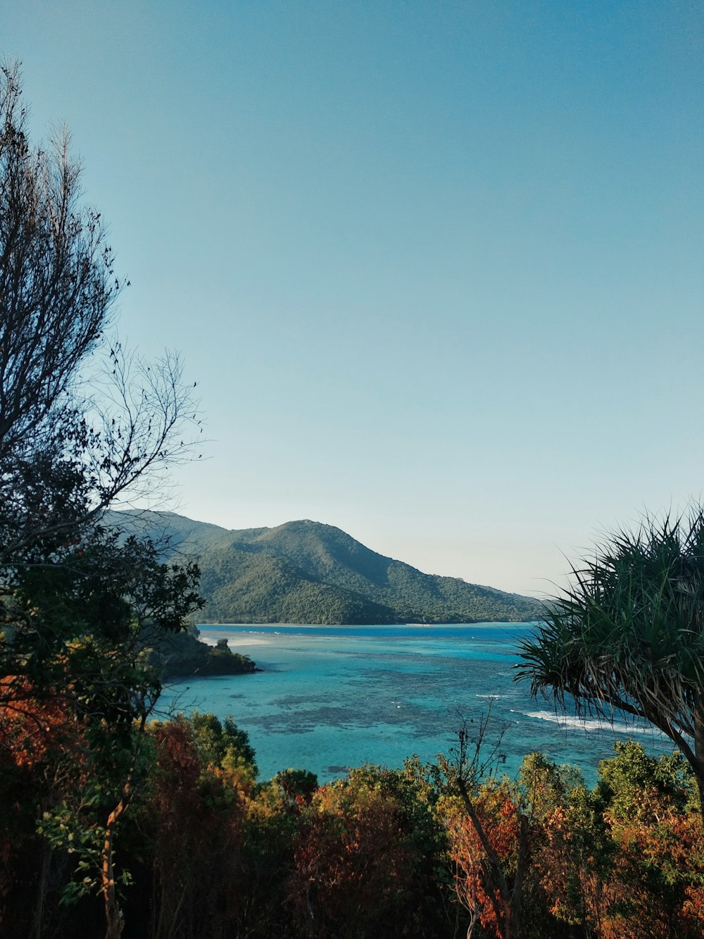 body of water in front of mountain under blue sky