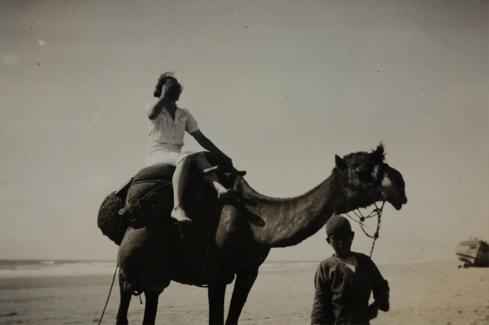 ラクダに乗る女性のグレースケール写真