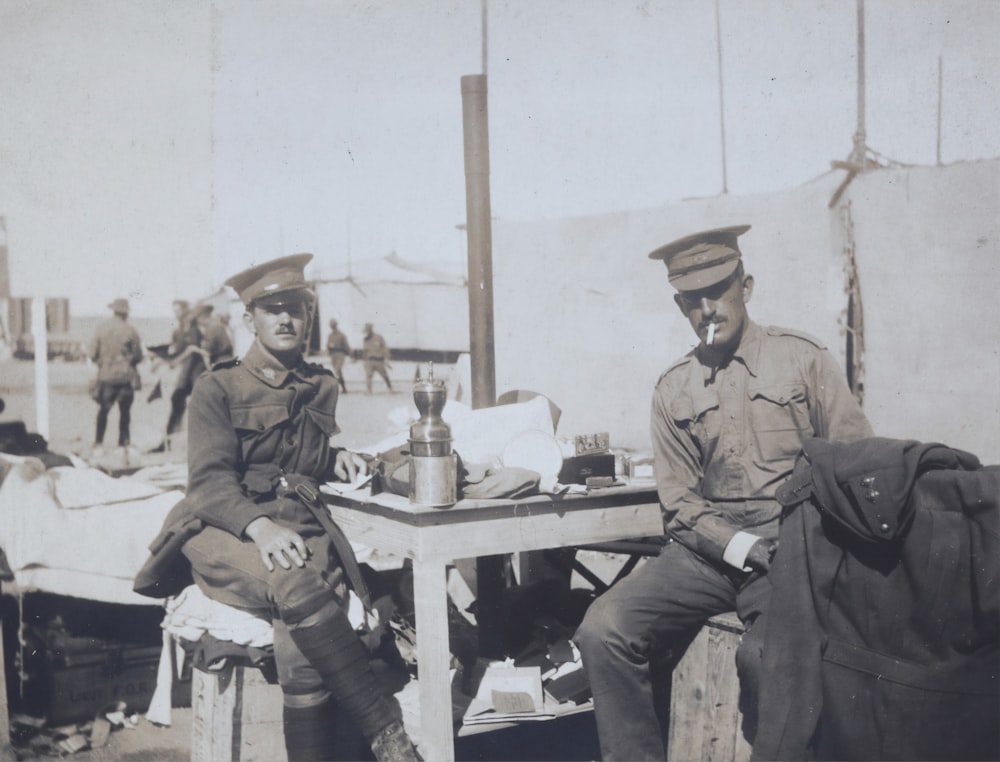 two men wearing police hats sitting in front of table