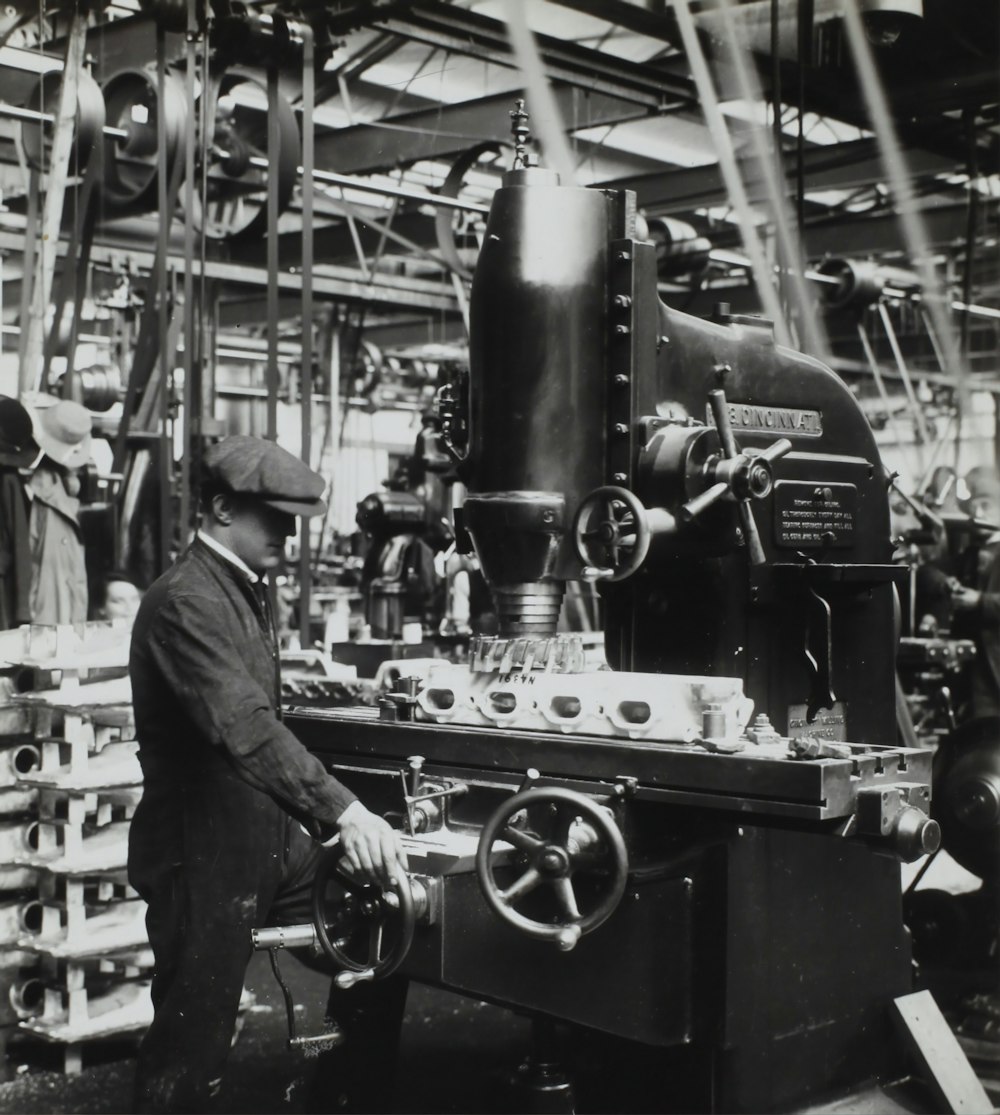 grayscale photography of man facing mechanical machine