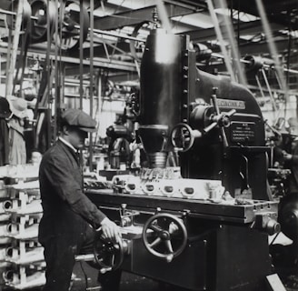 grayscale photography of man facing mechanical machine