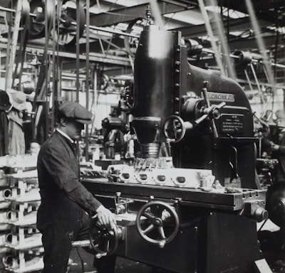 grayscale photography of man facing mechanical machine