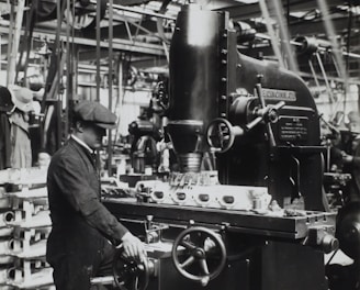 grayscale photography of man facing mechanical machine