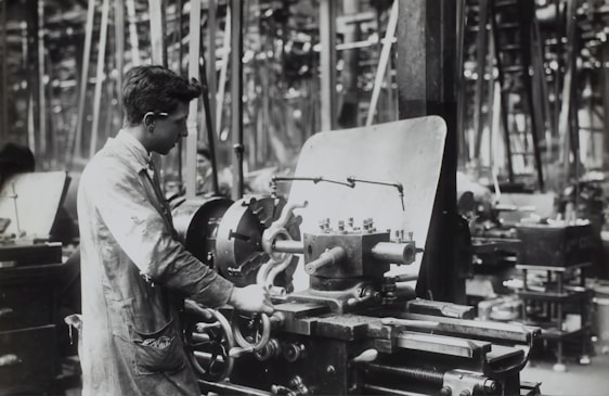 A skilled technician repairing an industrial metalworking machine in a workshop.