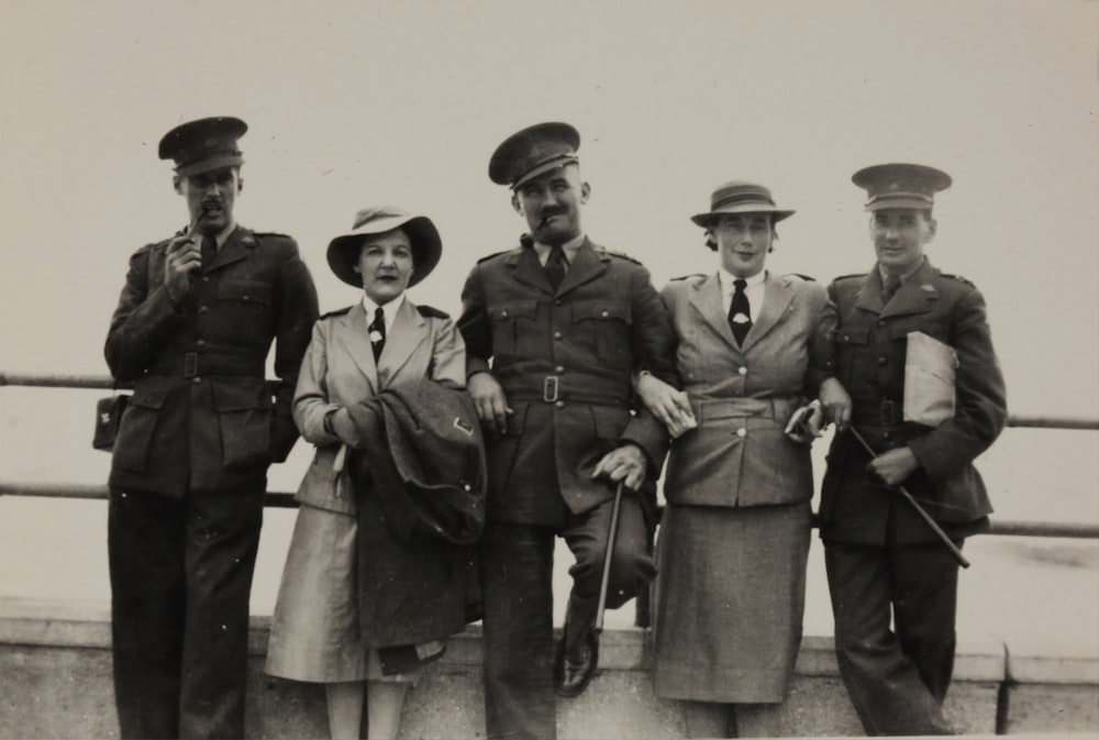 grayscale photo of men and women leaning on handrail