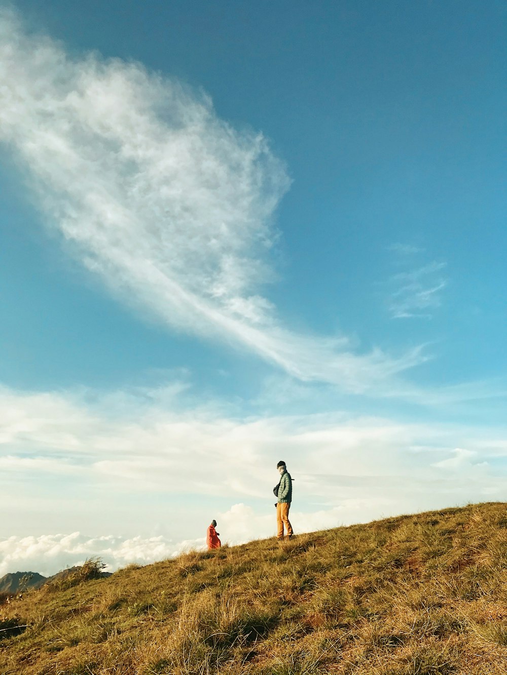 man standing on hill under blue sky