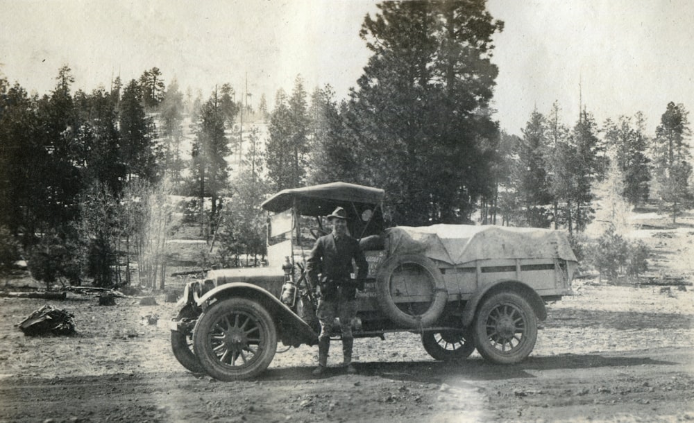 grayscale photo of man standing beside vintage truck