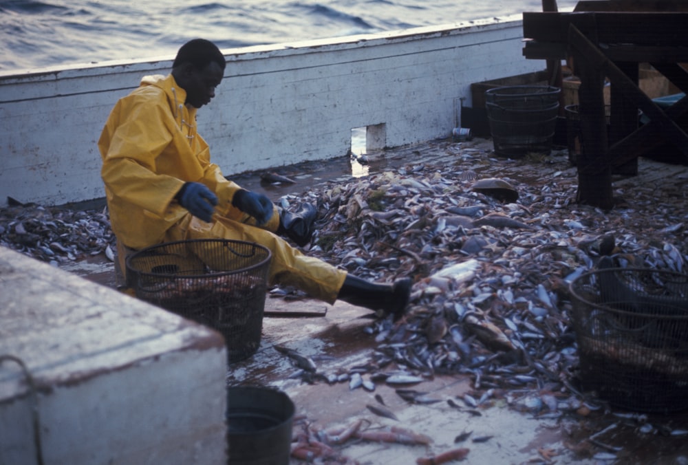 man sitting on stool infront of bunch of fish