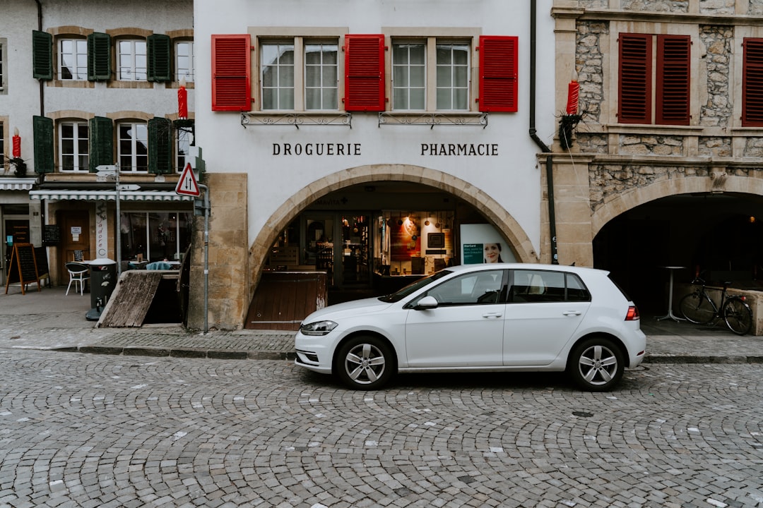 parked white Volkswagen 5-door hatchback in front of Droguerie Pharmacie building