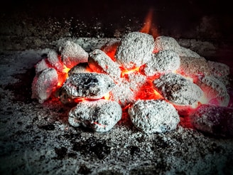 Close-up photo of glowing charcoal briquettes stacked in a neat pile