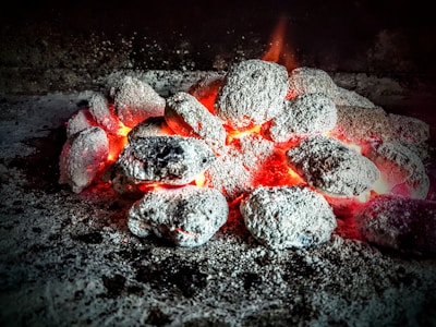 Stack of neatly arranged mesquite charcoal bags glowing under warm lighting with a hint of smoke
