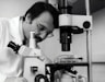 grayscale photography of doctor using microscope