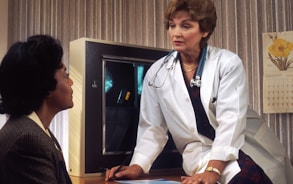 doctor sitting on desk talking to sitting woman