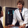 doctor sitting on desk talking to sitting woman