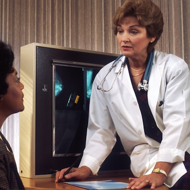 doctor sitting on desk talking to sitting woman