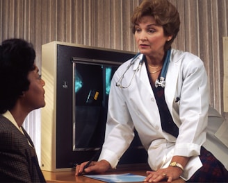 doctor sitting on desk talking to sitting woman