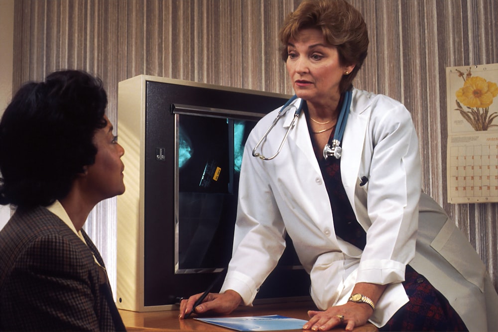 doctor sitting on desk talking to sitting woman