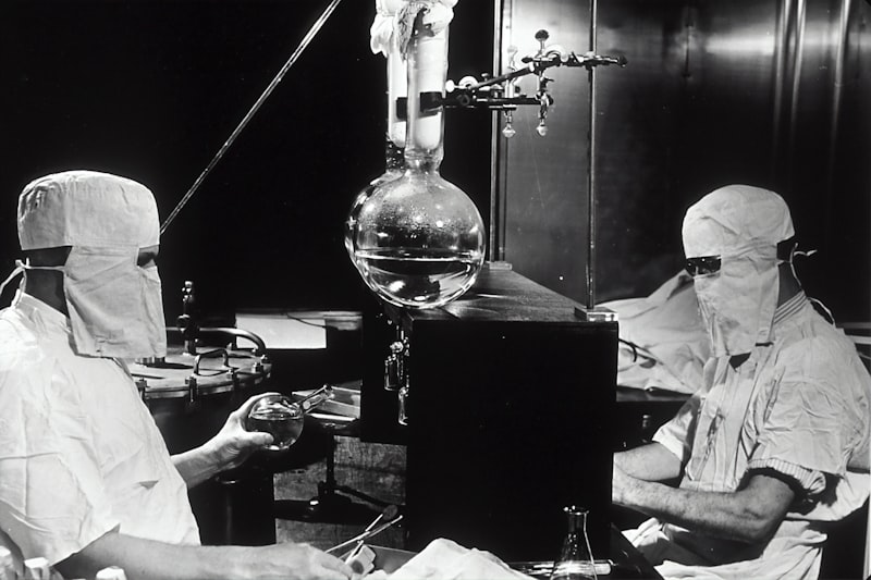 Researchers in cleanroom gear working with laboratory glassware
