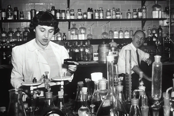 Close-up of laboratory technicians carefully measuring pharmaceutical compounds in a bright, clean lab.