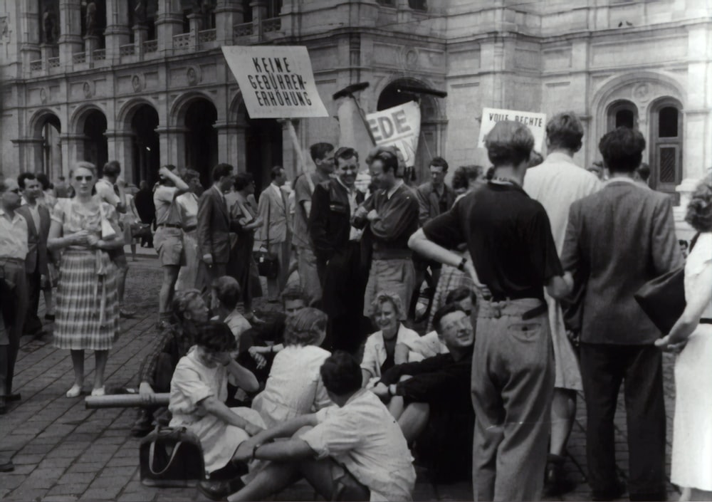 greyscale photo of people standing near building