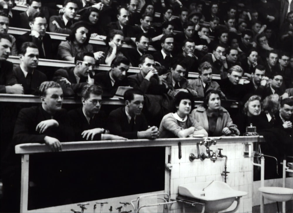 Fotografía en escala de grises de personas sentadas en una silla de multitudes