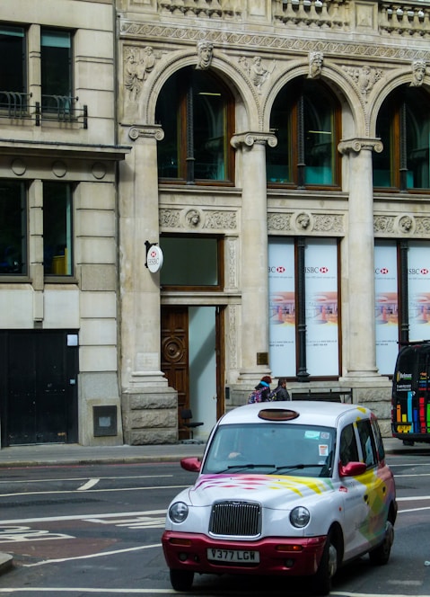 A clean, modern taxi parked by a Folkestone street with a driver greeting a smiling passenger.
