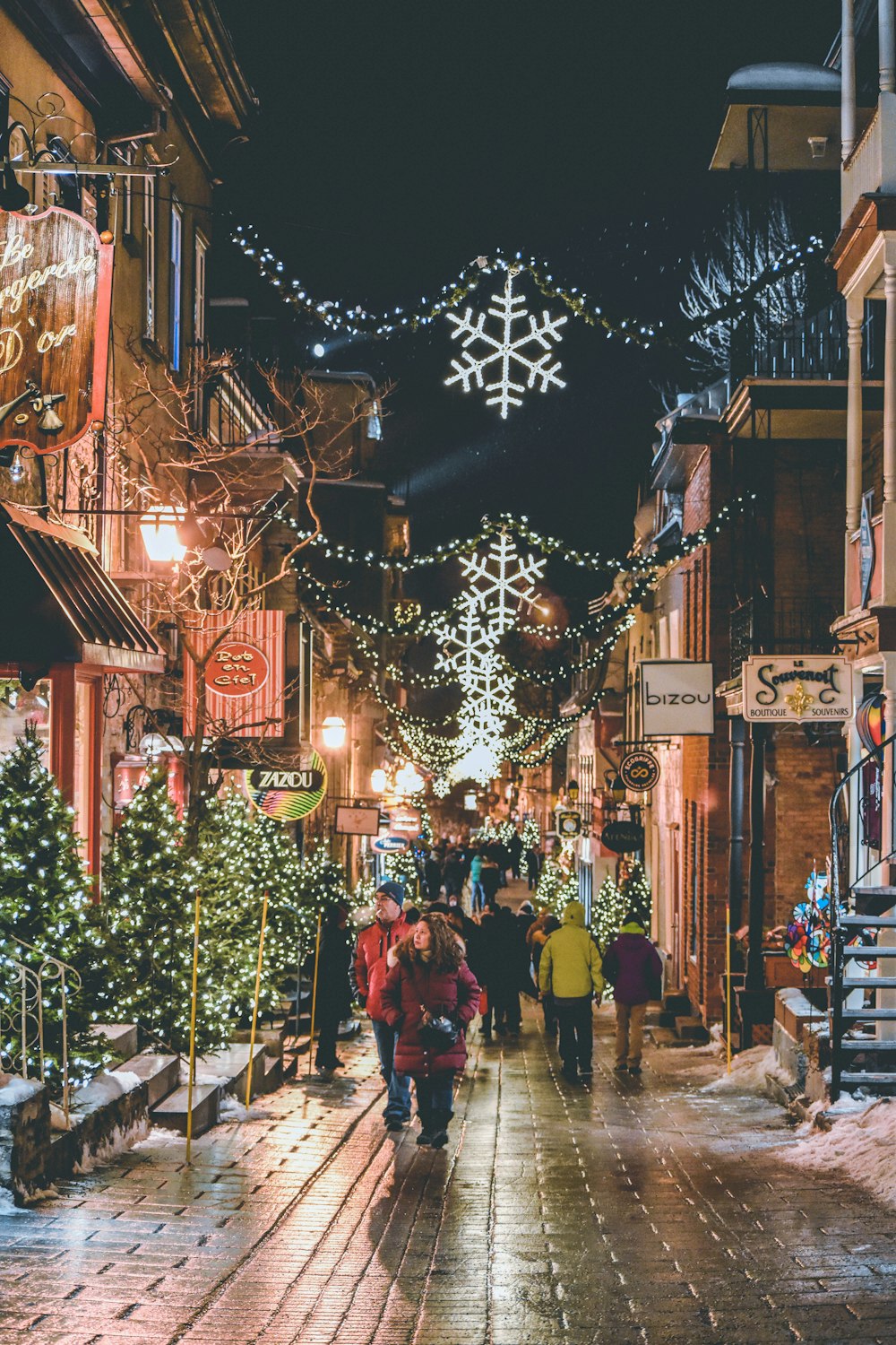 밤 시간에 크리스마스 트리 근처 거리를 걷는 사람들