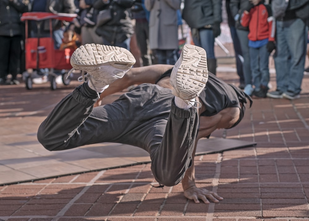 man wearing grey pants doing tricks on street