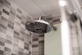Technician installing a modern showerhead in a bright bathroom.