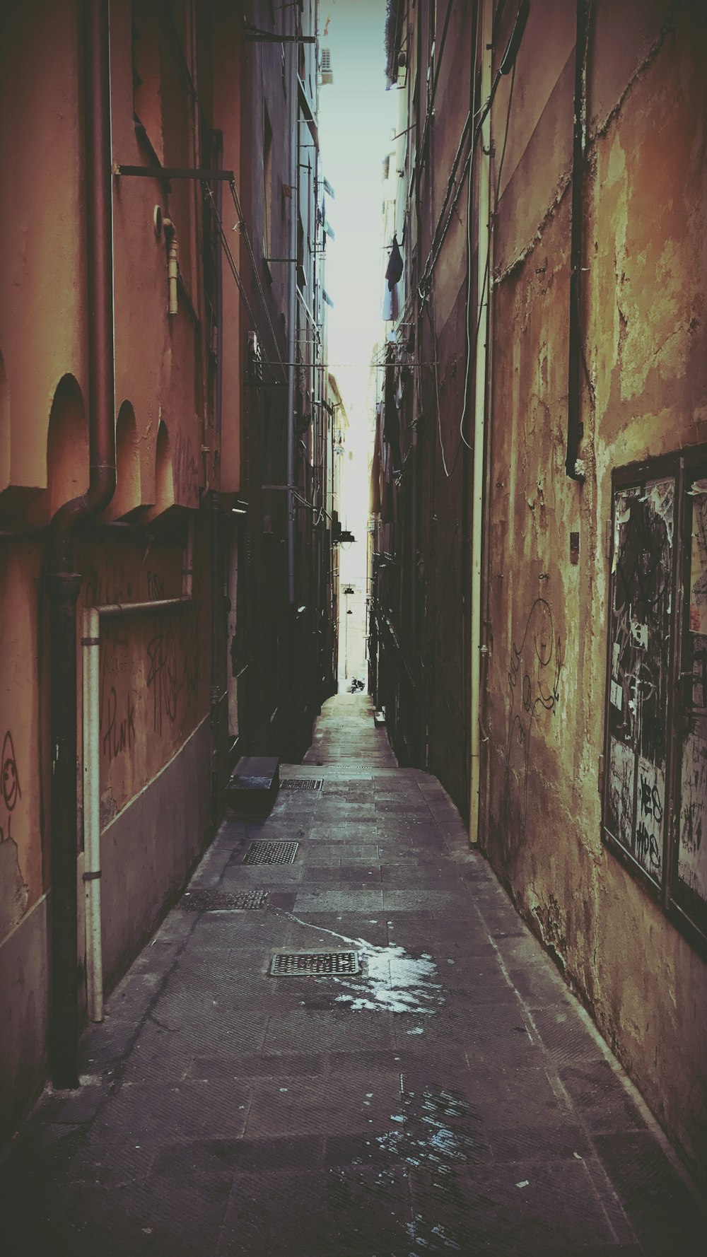 a narrow alley way with graffiti on the walls