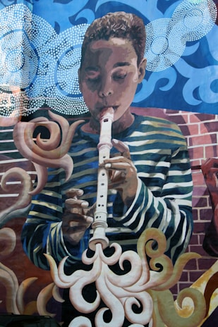A mural depicting a young person playing a recorder. The background features swirling patterns and abstract forms, with clouds and smoke-like shapes surrounding the figure. The artwork incorporates vibrant colors and dynamic lines.