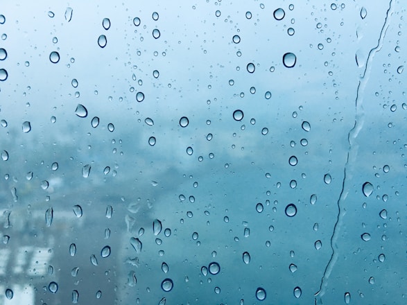 A close-up of a sensor device with raindrops, fog, and snow in the background illustrating weather effects.